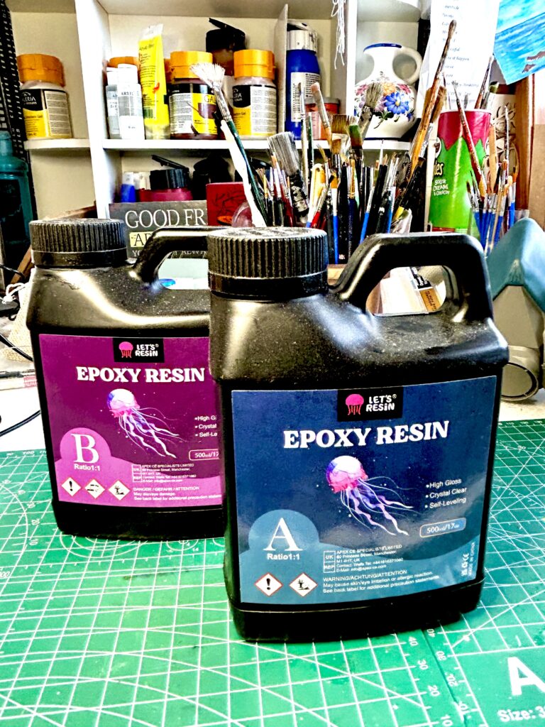 two bottles of epoxy resin on a craft table ready to be mixed