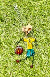 Outdoor photography of hand made products. A football character bag charm photographed on a grass background in natural light 